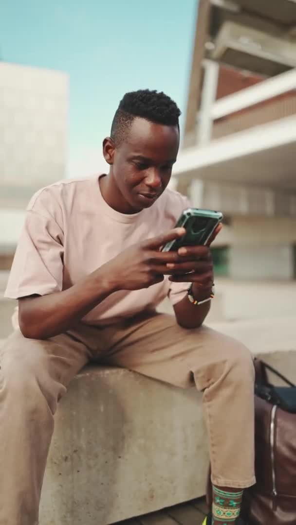 Vertical Video Young African Student Sits University Uses Cellphone Writes — Vídeos de Stock