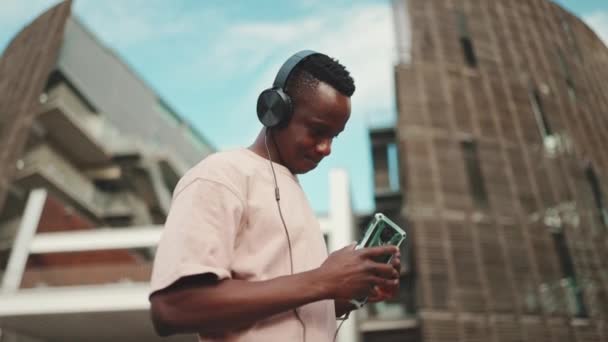 Profile Young African Student Stands University Headphones Uses Phone Listens — Vídeos de Stock