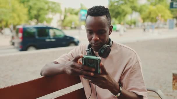 Young African Student Sits Bench University Headphones Uses Phone — Vídeo de Stock