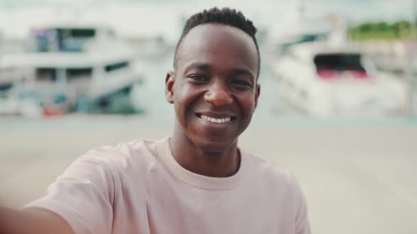 Smiling Young African Guy Uses Phone While Standing Embankment Yachts — Vídeo de Stock