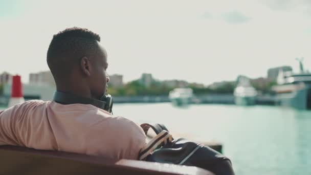 Clouse Young African Guy Relaxes Sitting Bench Port Yachts Ships — Vídeo de Stock