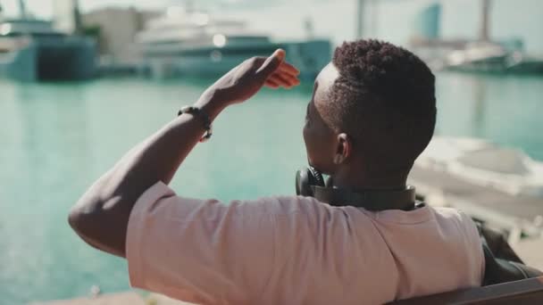 Clouse Young African Guy Relaxes Sitting Bench Port Yachts Ships — Vídeo de Stock