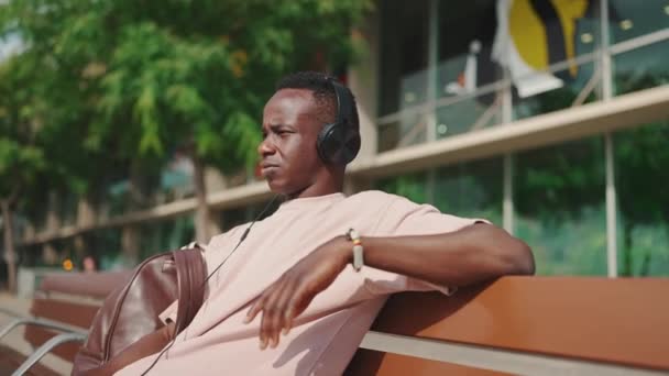 Young African Guy Relaxes Sitting Bench Listens Music Headphones — Vídeo de Stock