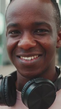 Clouse, gülümseyen genç Afrikalı öğrenci üniversitenin önünde kulaklıklarla dikiliyor.