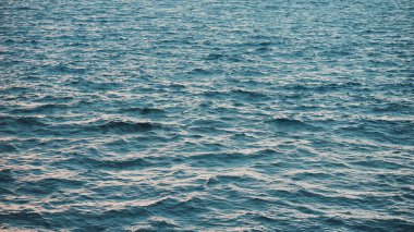 Suyun üzerinde güneş parlıyor. Suyun yüzeyinde güneş parıltıları olan doğal bir arka plan. Sonu gelmeyen deniz suyu yüzeyi manzarası ve güneş alevi. Su yüzeyinin dokusu güneş ışınlarının deniz yansıması.