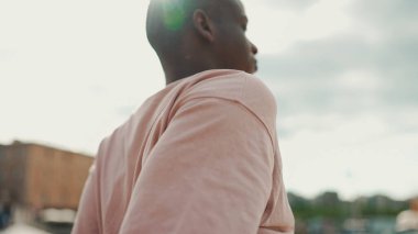 Genç Afrikalı adam deniz kenarında oturuyor, yat ve gemilerin arka planında. Arka plan