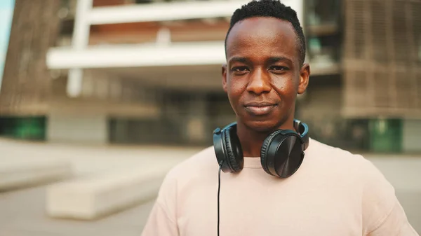 Young African Student Stands University Wearing Headphones Smiling Looking Camera — Φωτογραφία Αρχείου