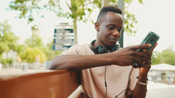 Smiling Young African Student Sits Bench University Headphones Uses Phone — Stockfoto