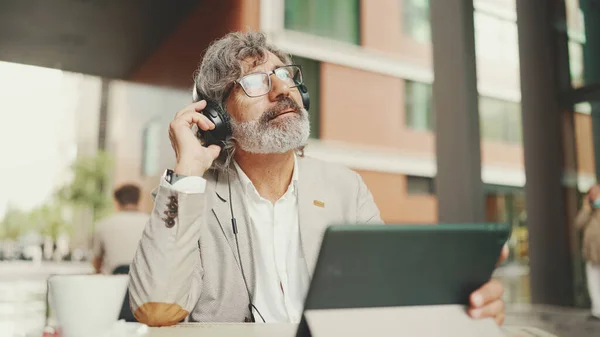 Mature Businessman Beard Eyeglasses Headphones Sits Outdoor Cafe Works Using — Foto de Stock