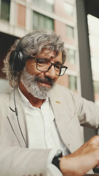 Mature Businessman Beard Eyeglasses Headphones Sits Outdoor Cafe Works Using — Fotografia de Stock