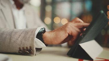 Tablet üzerinde çalışan yetişkin işadamlarının yakın çekimleri açık kafede oturur.