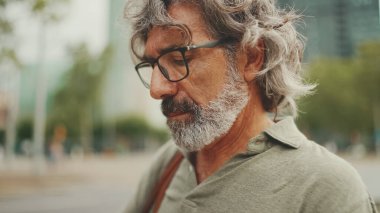 Clouse-up, friendly middle-aged man with gray hair and beard wearing casual clothes 