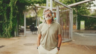 Dost canlısı, orta yaşlı, gri saçlı, sakallı sıradan kıyafetler giyen kulaklıkla müzik dinleyen bir adam. Gözlüklü, olgun bir beyefendi açık havada müzik dinlemekten hoşlanır.