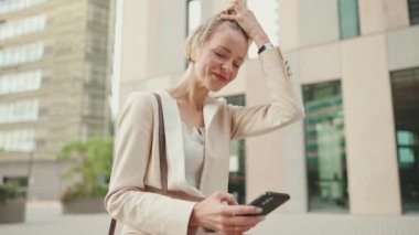 Businesswoman with blond hair using cellphone outside on the street
