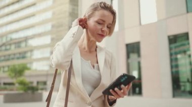 Businesswoman with blond hair using cellphone outside on the street