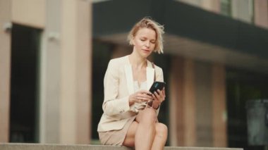 Businesswoman with blond hair typing on cellphone