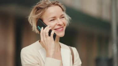 Close up, smiling businesswoman with blond hair talking on cellphone