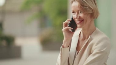Close up, smiling businesswoman with blond hair talking on cellphone