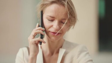 Close up, smiling businesswoman with blond hair talking on cellphone