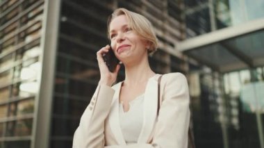 Happy businesswoman with blond hair talking on cellphone, good deal, success