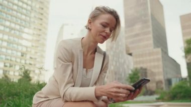 Businesswoman with blond hair typing on cellphone