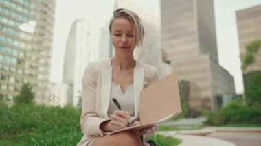 Businesswoman with blond hair wearing beige suit writes notes