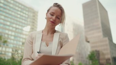 Businesswoman with blond hair wearing beige suit writes notes