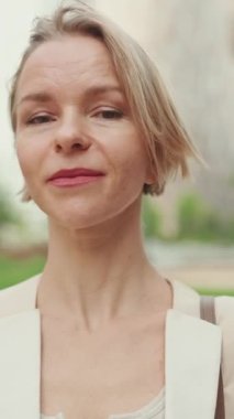 VERTICAL VIDEO: Close up, businesswoman looks at the camera