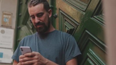 Young man with beard uses an application on smartphone