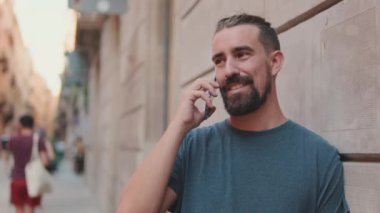 Close-up of young man with beard talking on cellphone against the background of the old city