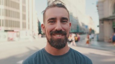 Portrait of young smiling man with beard standing in front of busy intersection