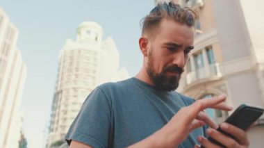 Close up, young man with beard uses map application on mobile phone