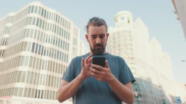 Young man with beard uses map application on mobile phone