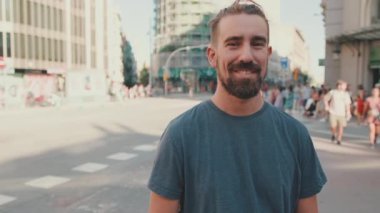 Young smiling man with beard standing in front of busy intersection