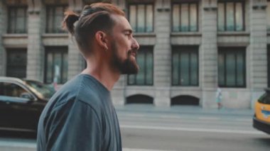 Profile of young smiling man with beard walking down the street