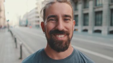 Portrait of young man with beard looking and smiling at the camera