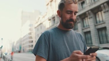 Young man with beard uses smartphone on road background