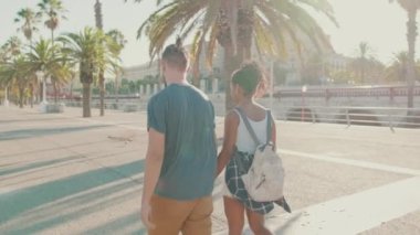 Interracial couple walks down the street holding hands