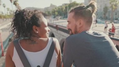 Close-up of an interracial couple standing on bridge. Back view