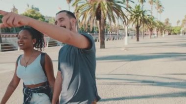 Smiling interracial couple walking down the street holding hands
