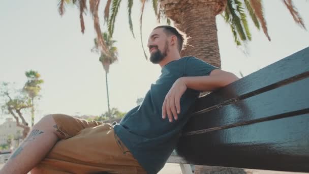 Young Smiling Man Beard Sits Rests Bench Backlight — Stock Video