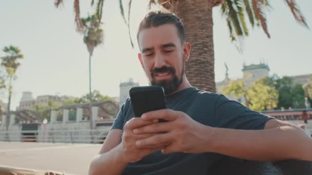 Young Smiling Man Beard Sits Bench Uses Cellphone — Vídeos de Stock