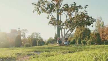Happy smiling interracial couple talking while sitting on the grass in the park