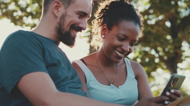 Happy Smiling Interracial Couple Watching Video Mobile Phone While Sitting — Vídeo de Stock