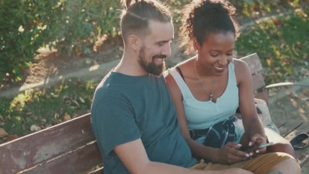 Happy Smiling Interracial Couple Watching Video Mobile Phone While Sitting — Stock videók