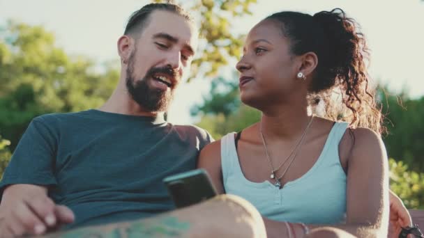 Happy Interracial Couple Talking While Sitting Bench Using Cellphone — Stock videók