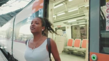 Young mixed race woman getting off the train at the railway station