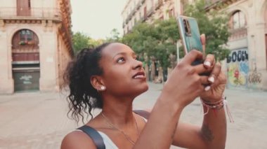Young mixed race woman uses cell phone, takes photo of the old city