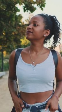 VERTICAL VIDEO: Laughing young mixed race woman walking along path in the park