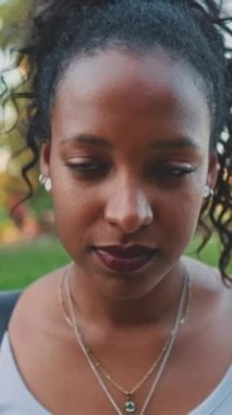 VERTICAL VIDEO: Close up, smiling young mixed race woman looking at camera